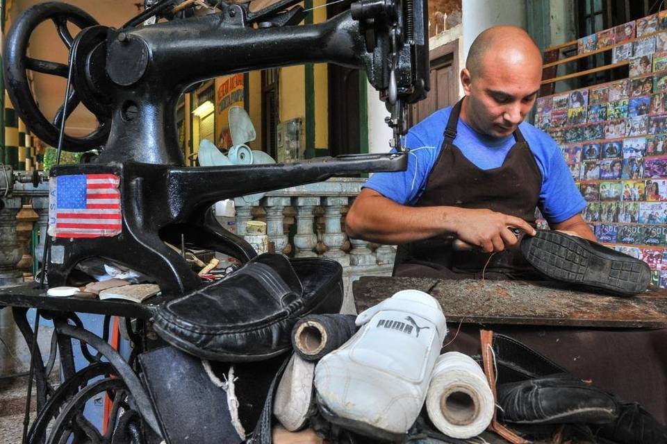 A private cobbler works near a U.S. flag in Havana
